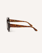 Aide view of chunky acetate frame in an aviator shape. You can really see the thickness of the frame. Tortoise frame with green lenses.