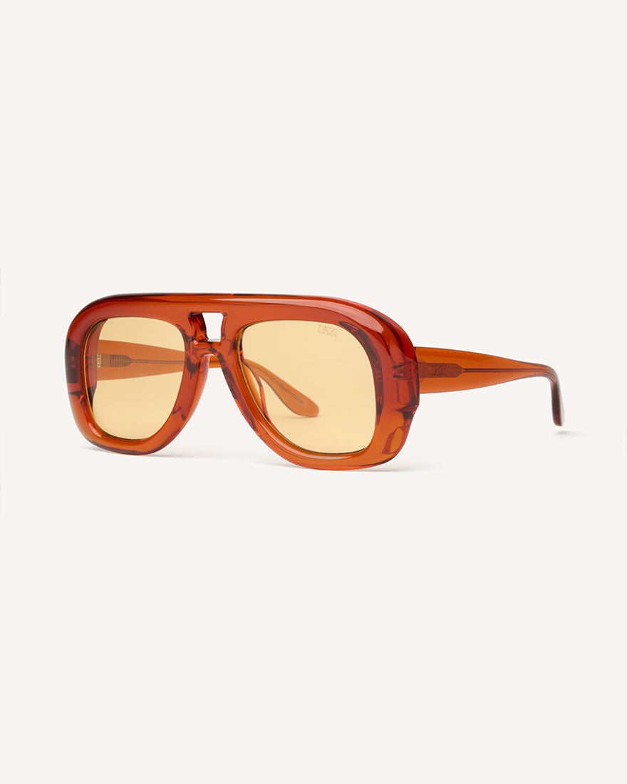 angled view of chunky acetate frame in an aviator shape. Orange frame with yellow lenses.