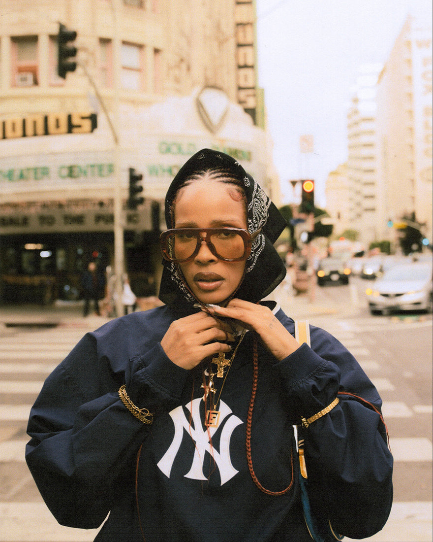 Model wearing chunky acetate frame in an aviator shape. Caramel frame with yellow lenses.