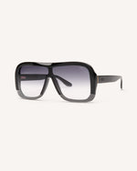 Angled view of stylish acetate sunglasses with a modern design, featuring a sleek black frame and subtly faded black lens.